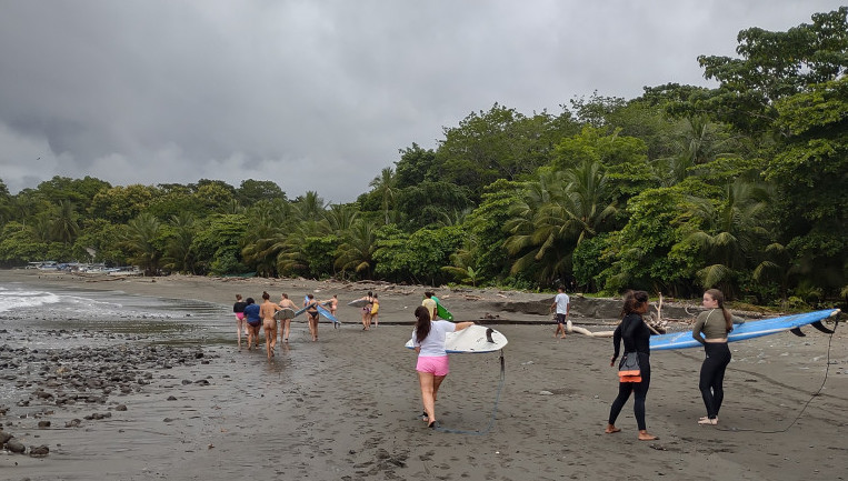 Many surfers walk on a beach in Costa Rica.